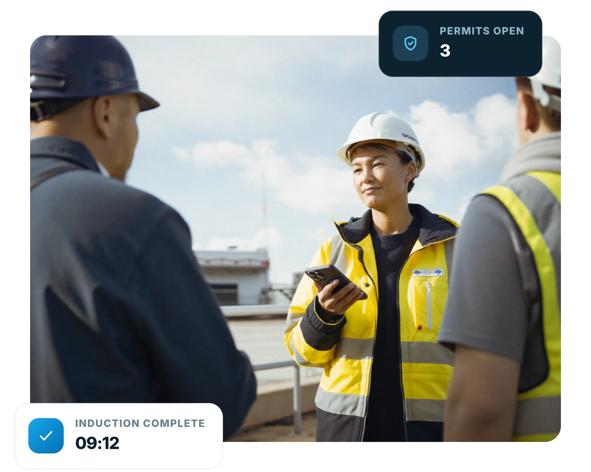 Health and safety advisor in hi-vis briefing workers at a site entrance with a phone in her hand