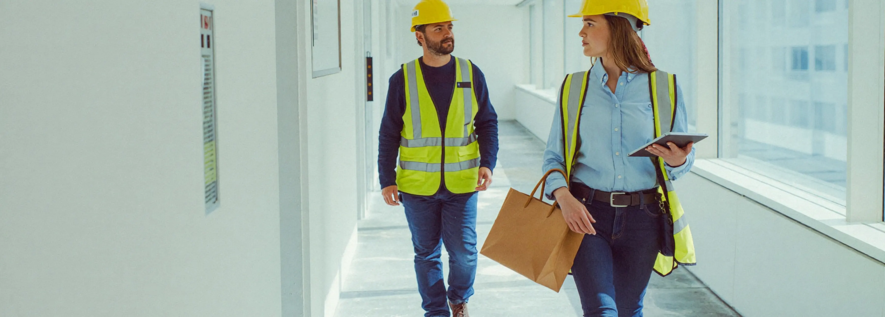 Two site managers reviewing quality records on a tablet inside a completed building