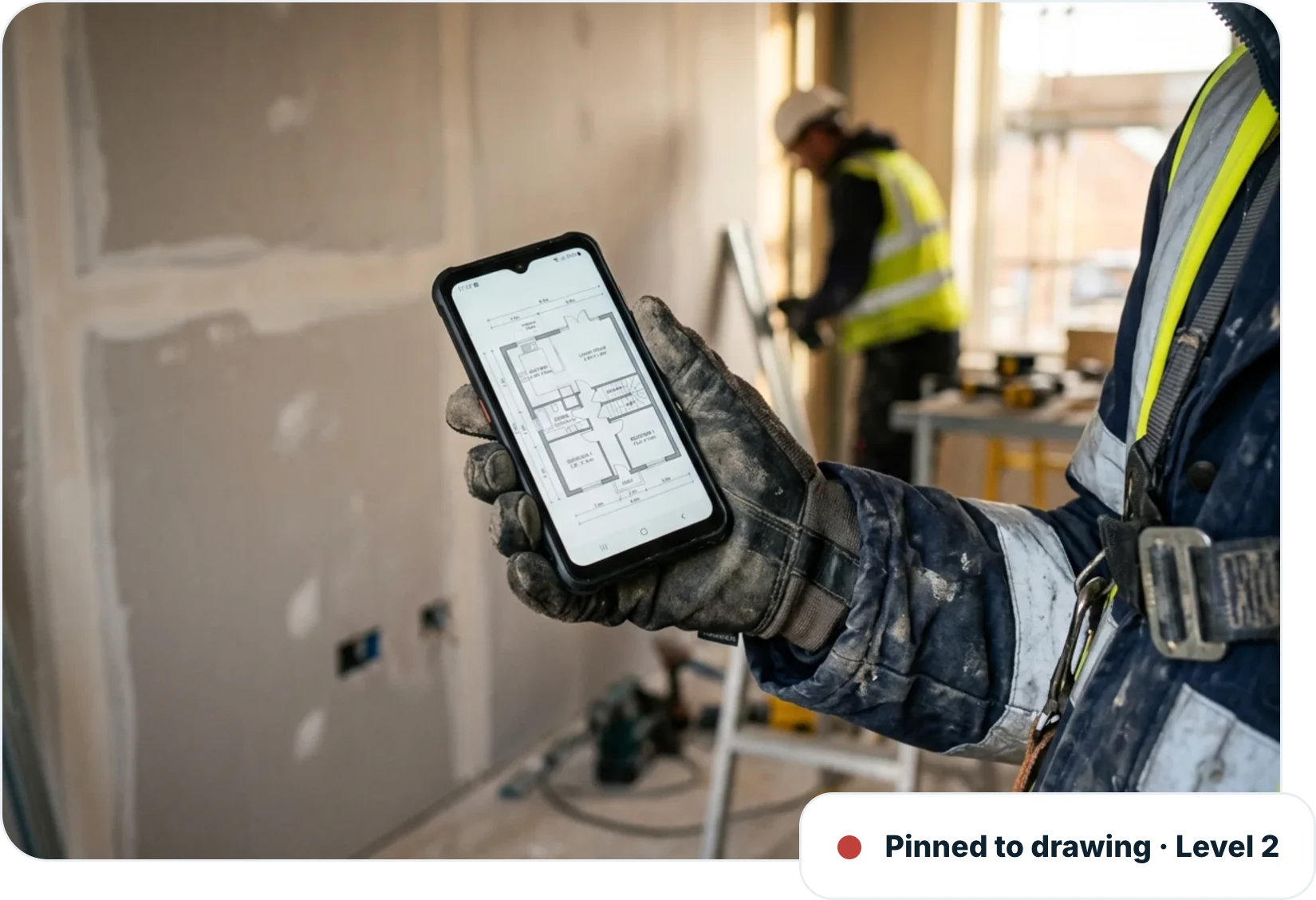 Operative holding a phone showing a floor plan on site, with a snag pinned to the drawing on level 2