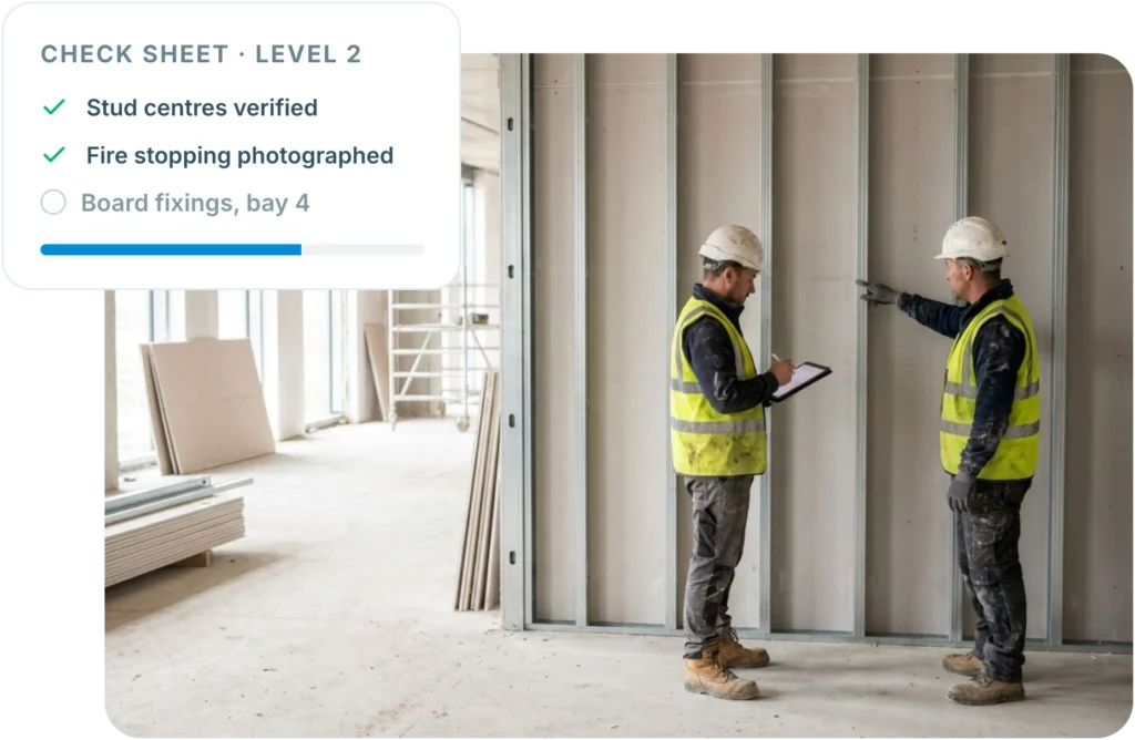 Two subcontractor operatives checking stud centres and fire stopping against an Insite check sheet at the work face