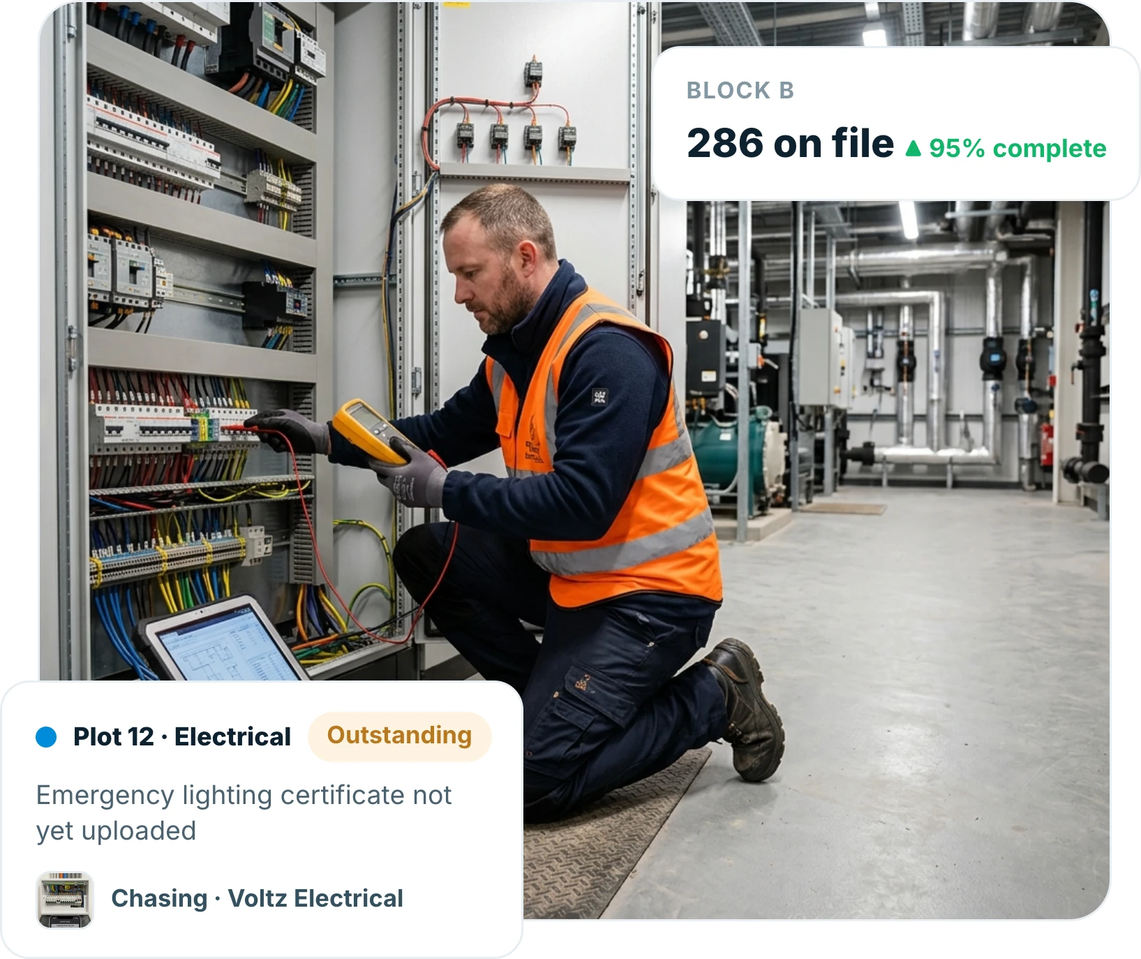 Electrician kneeling at a new distribution board taking a test reading with a multimeter next to a laptop